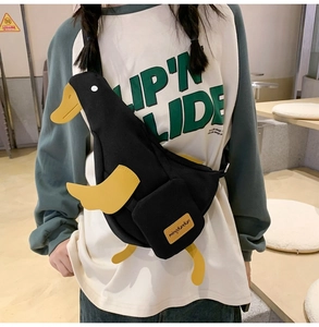 Detail of a black canvas crossbody bag featuring a 3D cartoon duck design and strap