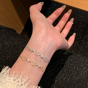 Detail of 18k gold and silver bracelets featuring interlocked loops and sparkling zircons