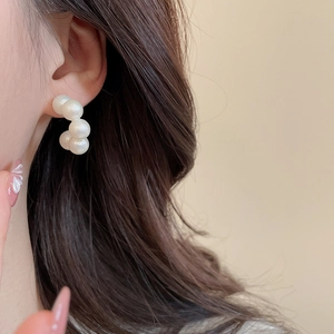 Close-up of minimalist C-shaped pearl earrings on model with white pearl detail