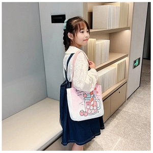 Pink canvas tote bag featuring strawberry milk cartoon print worn by a model