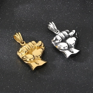 Polished gold and silver fist pendants in stainless steel on dark textured surface