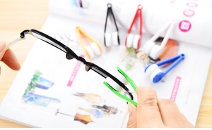 Close-up of green microfiber cleaning tool wiping a lens on black frame glasses