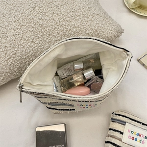Close-up of striped fabric cosmetic bag with spacious interior and metal zipper detail