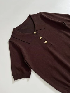 Detail of dark brown knit polo shirt with golden flower buttons and pearl accents