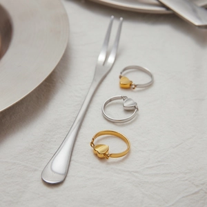Nahaufnahme von drei 18K Gold- und Silber-Herzanhänger-Ringen auf weißem Stoff