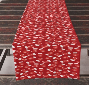 Detailed pattern of white Christmas gloves and socks on a red fabric holiday table runner