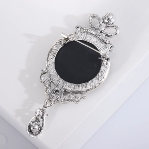 Detail of silver vintage brooch with black oval inlay, crown motif and teardrop pendant