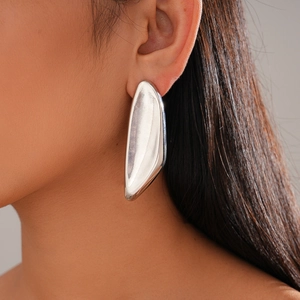 Irregular geometric oval earrings with a sculptural silver finish on a female model