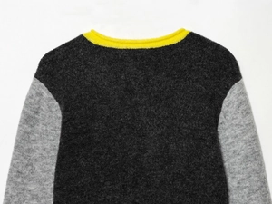 Detail shot of color-blocked knit sweater featuring grey panels and yellow ribbed neckline