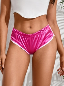 Dettaglio degli shorts da yoga in raso rosa con profili a contrasto e vita alta