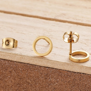 Polished gold circular stud earrings with butterfly backs on minimalist wooden block