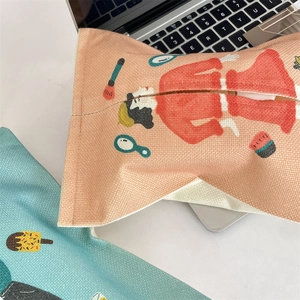 Close-up of textured canvas car tissue holder with cartoon makeup illustration on desk