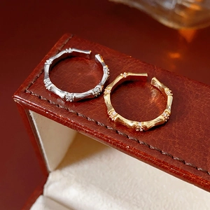 Détails macro de bagues en bambou or et argent avec zircons sur boîte en cuir