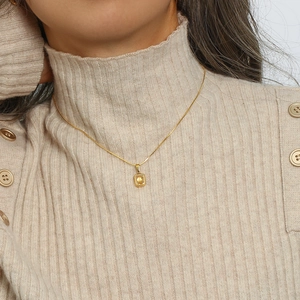 Detailed close-up of a golden paperclip chain necklace with a square yellow zircon pendant
