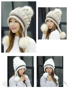 Dettaglio di un cappello in maglia spessa con paraorecchie e tre pompon in finta pelliccia