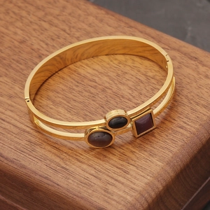 Detailed view of a gold double-layer bangle featuring black and dark red gemstones