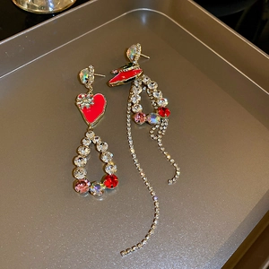 Detail of asymmetric red heart and high heel earrings with sparkling crystal tassels