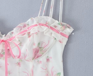 Detail of floral mini dress with pink rose print, ruffled neckline and ribbon bow tie
