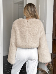 Vista posteriore di un cappotto corto di peluche beige con maniche lunghe e zip