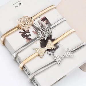 Détail de chaînes de taille élastiques en métal avec boucles en strass pomme et nœud