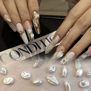 Detailed view of long stiletto press-on nails with 3D baroque pearls and gold textures