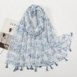 Detailed view of light blue floral voile scarf with delicate fringe tassels on the edge