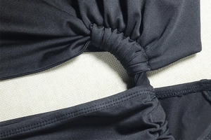 Macro shot of black ruched knit fabric and detailed shoulder seam on asymmetric dress