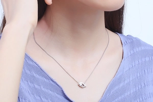 Close-up of a silver eye-shaped pendant necklace with pearl on a female model