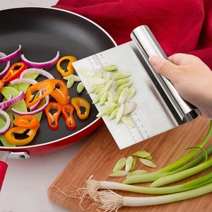 Detail of stainless steel dough scraper with measurements scooping greens into a red pan