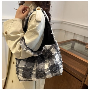 Détail d'un grand sac à bandoulière en tweed à carreaux noir et blanc avec franges