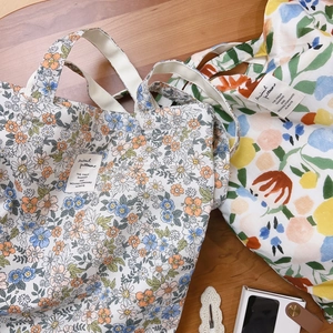 Borse tote in tela di cotone con stampa floreale e tracolle su fondo in legno