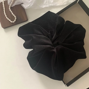 Close-up of a large black velvet hair scrunchie with soft pleated texture and pearls