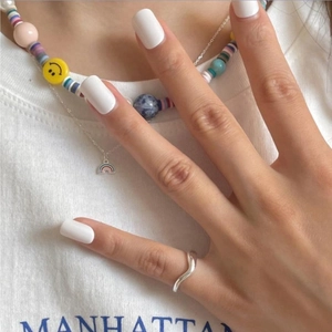 Polished silver wave ring on finger with white manicured nails and casual fashion style