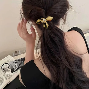 Close-up of golden flower hair clip with a center pearl on model's wavy brown hair