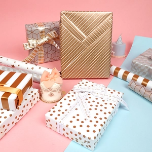 Metallic gold foil gift wrapping paper rolls with assorted patterns and wedding ribbons