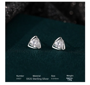 Macro shot of triangle S925 silver stud earrings with clear zircon on green velvet
