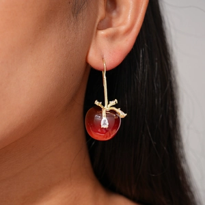 Gros plan détaillé des boucles d'oreilles cerises rouge foncé avec feuilles dorées et zircon