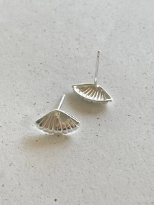 Macro detail of silver shell-shaped stud earrings with radial ribs and mirror finish