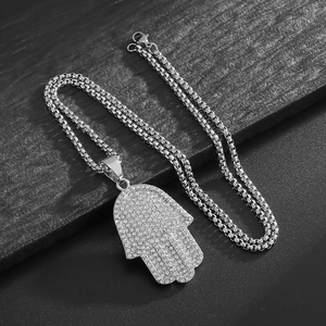 Hip hop silver Hamsa hand pendant necklace with rhinestones and beaded chain on dark background