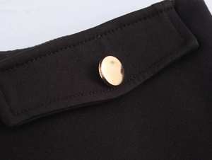Close-up of polished gold metal button on black fabric showing premium texture detail