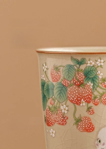 Detail of Ru kiln ceramic cup with ice-crack glaze finish and hand-painted strawberries