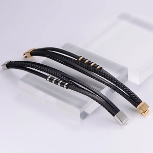 Detail of multi-layer woven black leather bracelets with gold and silver magnetic clasps