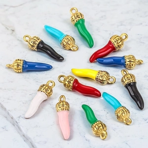 Colorful enamel chili pepper pendants with golden crown caps on white marble background