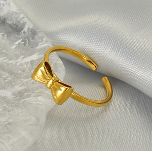 Detailed view of golden bow ring with brushed texture and adjustable open band design