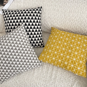 Detail view of geometric linen pillow covers in yellow and grey on soft white texture