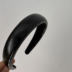 Close-up of a wide black glossy headband with a sleek polished finish for women