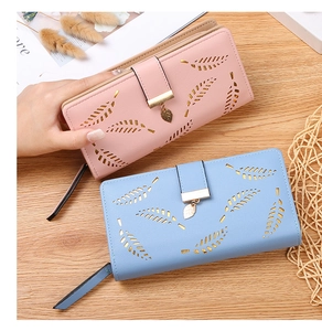 Close-up of long leaf cutout wallet with metal leaf pendant in pink and blue faux leather