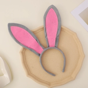 Cute gray and pink plush bunny ear headband on a beige decorative tray for Easter parties