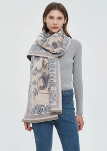 Detailed view of paisley and bird pattern on a beige scarf with blue fringe accents