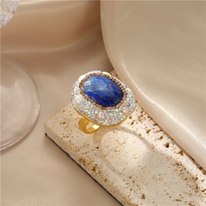 Macro detail of Baroque pearl ring with oval blue gemstone and gold finish on stone base